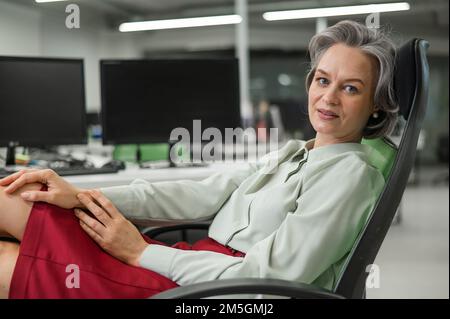 Donna caucasica matura tolse le scarpe e mise i piedi sul desktop in ufficio. Foto Stock