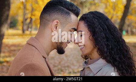 Amorevole coppia sposata in piedi fronte toccare e strofinare nasi toccare sorridente all'aperto multirazziale uomo e donna ragazza etnica e ragazzo Foto Stock