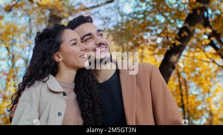 Felice amanti marito e moglie etnico multirazziale sposato coppia nel parco autunnale sorridente donna caucasica con uomo ispanico all'aperto ragazzo e ragazza Foto Stock