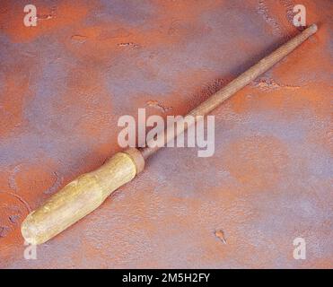 Vecchia raspa rotonda arrugginita con manico in legno su fondo arancione grunge Foto Stock