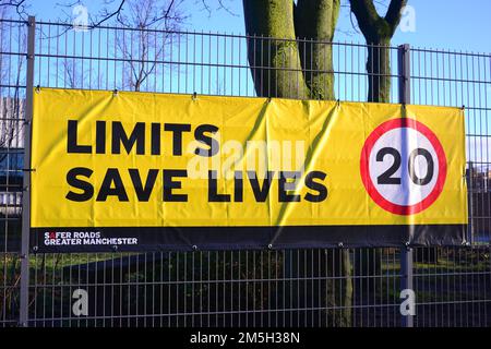 Il banner del limite di velocità dice "Limits Save Lives" (limiti salvare vite) con un suggerimento di 20 miglia all'ora sul recinto di una scuola a Manchester, Regno Unito Foto Stock