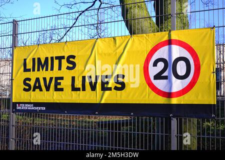 Il banner del limite di velocità dice "Limits Save Lives" (limiti salvare vite) con un suggerimento di 20 miglia all'ora sul recinto di una scuola a Manchester, Regno Unito Foto Stock