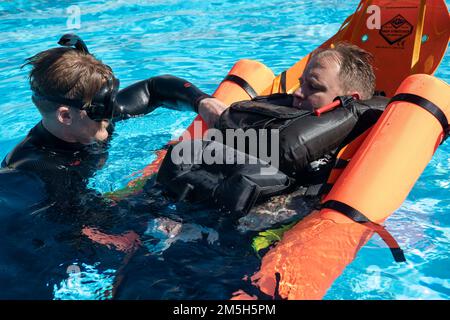 220317-N-EV253-1143 SAN DIEGO (17 marzo 2022) – Naval Aircrewmen (elicottero) 1st Classe Nathan Reed, sinistra, protegge Naval Aircrewmen (elicottero) 1st Classe Kristopher Sellmeyer, destra, entrambi assegnati al Capo delle operazioni navali (CNO) Search and Rescue Model Manager (SARMM) componente di Helicopter Sea Combat Squadron, (HSC) 3 In uno SKEDCO Rapid Deployment Flotation System, un apparato di recupero del personale progettato per fornire un rapido salvataggio in acqua, durante test tattici, tecnici e procedurali nella piscina dell'equipaggio a bordo della Naval Air Station North Island. Lo scopo dell'evoluzione era quello di valutare il Th Foto Stock