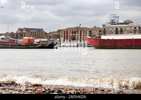 Ex magazzini che fiancheggiano il Tamigi a Wapping dietro chiatte Foto Stock