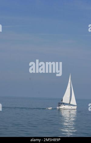 Lake Erie Coastal Ohio Trail - Barca a vela sul lago Erie. Il cielo e l'acqua si fondono mentre una barca a vela scivola lungo il tranquillo lago Erie. Lago Erie, Ohio (41,511° N 82,063° W) Foto Stock