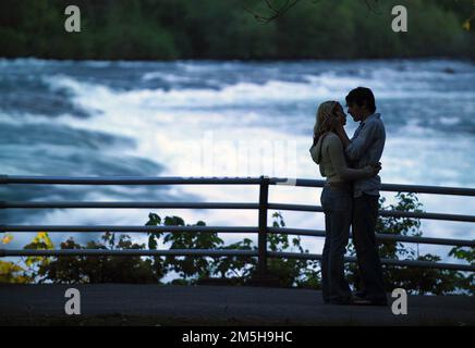 Great Lakes Seaway Trail - Love at Niagara Falls. Questa coppia gode di un momento insieme, sileted dalle acque infurianti delle cascate del Niagara. Le Cascate del Niagara sono una delle destinazioni per la luna di miele più popolari del paese. Cascate del Niagara, New York Foto Stock