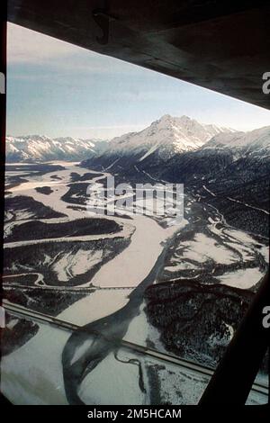 Glenn Highway - Aerial of Knik River Valley. Ciò mostra la vicinanza delle Montagne di Chugach e del Pioneer Peak alla Glenn Highway, entrando nel Matanuska Susitna Borough al miglio 30 della Glenn Highway. La New Glenn Highway è in primo piano, seguita dal ponte ferroviario dell'Alaska. L'Old Glenn Highway o Palmer Alternate, a 19 miglia di strada panoramica, può essere visto nel mezzo proprio alla base delle montagne. Alaska Foto Stock