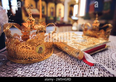 Un primo piano di una corona d'oro con l'icona di Maria e Cristo su di essa e una Bibbia su un tavolo Foto Stock