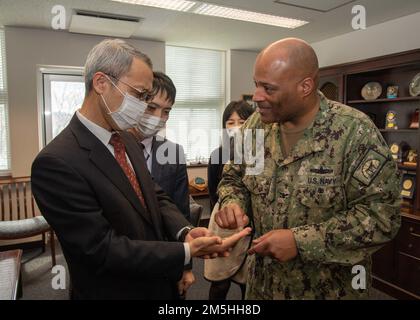 David Adams, Comandante, Fleet Activities Sasebo (CFAS) dà una moneta di comando al capo della polizia di Sasebo Tamotsu Ueki durante un incontro di congedo per Ueki al 18 marzo 2022. CFAS ha fornito, mantenuto e gestito strutture e servizi di base per potenziare le forze alleate e statunitensi dislocate nel futuro, fornendo al contempo un supporto superiore alle loro famiglie e alla comunità. Foto Stock
