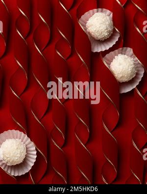 Praline di cocco su merletti curvy rosso velluto, dessert festivo concetto sfondo Foto Stock