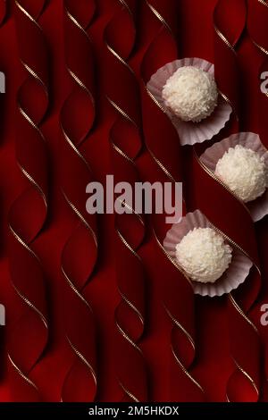 Praline di cocco su merletti curvy rosso velluto, dessert festivo concetto sfondo Foto Stock