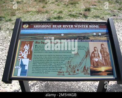 Pioneer Historic Byway - cartello interpretativo al massacro di Bear River Sito: "Shoshone Bear River Winter Home". BIA Ogoi o Big River hanno fornito una casa invernale per lo Shoshone. Le sorgenti termali e una fertile valle furono un ringiovanimento fisico e spirituale per le famiglie Shoshone che vivevano qui. Questo segno include seppia tonica, foto storiche degli indiani Shoshone. Posizione: Bear River Massacre Overlook, Idaho (42,151° N 111,908° W) Foto Stock