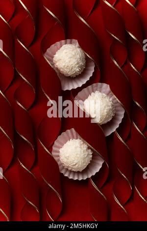 Praline di cocco su merletti curvy rosso velluto, dessert festivo concetto sfondo Foto Stock