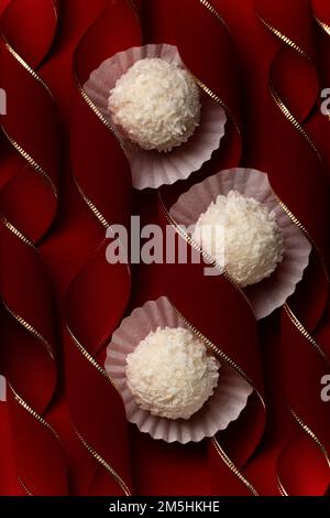 Praline di cocco su merletti curvy rosso velluto, dessert festivo concetto sfondo Foto Stock