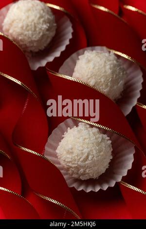 Praline di cocco su merletti curvy rosso velluto, dessert festivo concetto sfondo Foto Stock