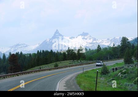 Beartooth Highway - Scenic Pilot e Index Peaks. La lussureggiante erba verde fienga la strada, mentre la neve copre le vette pilota e indice. Posizione: Scenic Pilot and Index Peaks, Wyoming (44,958° N 109,813° W) Foto Stock