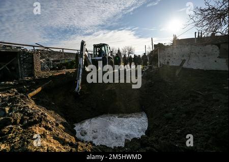 STEPNE, UCRAINA - 29 DICEMBRE 2022 - uomini e un escavatore sono visti fuori di una casa distrutta in un attacco missilistico russo S-300 al villaggio di Stepne, Zap Foto Stock