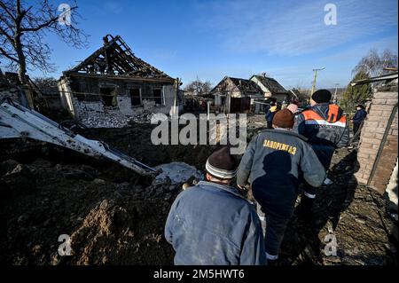 STEPNE, UCRAINA - 29 DICEMBRE 2022 - i lavoratori di servizi pubblici rimangono vicino ad una casa distrutta in un attacco missilistico russo S-300 contro il villaggio di Stepne, Zaporizhzhzhzhia Re Foto Stock