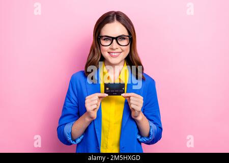 Foto di giovane donna business positivo indossare giacca blu camicia gialla tenere in plastica carta di credito wireless pagamento promo isolato su sfondo rosa Foto Stock