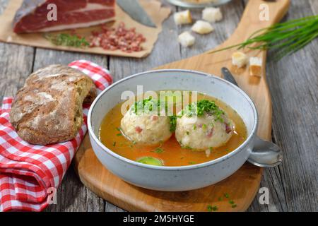 Deliziosa zuppa di gnocchi di pancetta altoatesina con brodo di manzo caldo e erba cipollina Foto Stock