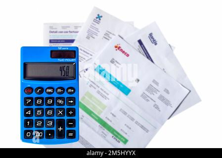 Calcolatrice tascabile blu e fatture/fatture di Eneco, fornitore di gas naturale ed elettricità, Proximus e Liantis su sfondo bianco Foto Stock