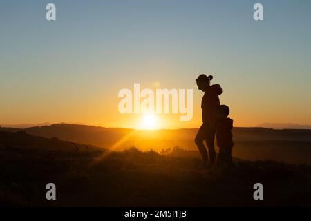 Madre e figlio si sono insilati al tramonto mentre camminavano Foto Stock