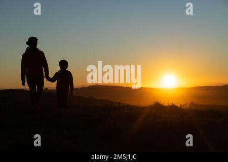 Madre e figlio si sono insilati al tramonto mentre camminavano Foto Stock