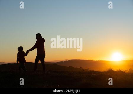 Madre e figlio si sono insilati al tramonto mentre camminavano Foto Stock