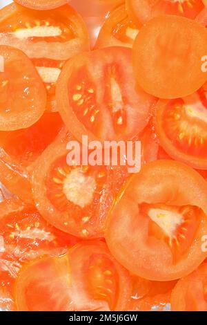 Primo piano fette fresche di pomodoro succoso su sfondo bianco. Fette di pomodoro in acqua frizzante su fondo bianco, primo piano. Immagine verticale. Foto Stock