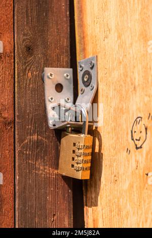 Lucchetto combinato su una porta in legno intemperiata Foto Stock