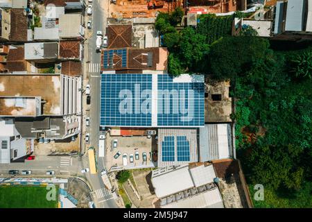 Foto aerea dall'alto verso il basso dei pannelli solari i moduli fotovoltaici montati su pannelli solari fotovoltaici a tetto piatto assorbono la luce solare come fonte di energia Foto Stock