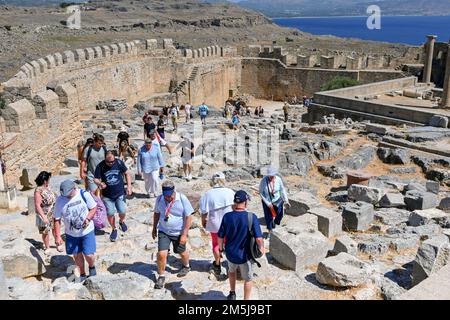 Lindos, Rodi, Grecia - 2022 maggio: I turisti che visitano le antiche rovine dell'acropoli sopra la città Foto Stock