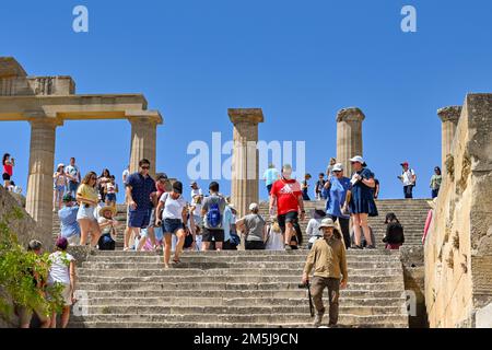 Lindos, Rodi, Grecia - 2022 maggio: I turisti che visitano le antiche rovine dell'acropoli sopra la città Foto Stock