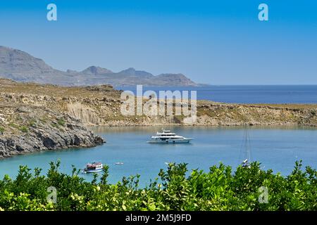 Lindos, Rodi, Grecia - Maggio 2022: Yacht di lusso ormeggiato in una piccola baia vicino alla città Foto Stock