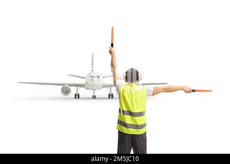 Immagine posteriore di un marshaller che segnala con le bacchette davanti ad un aeroplano isolato su sfondo bianco Foto Stock