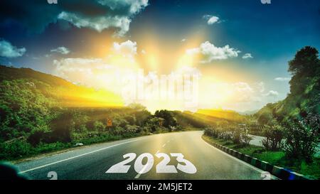 Nuovo anno 2023 o concetto dritto. Testo 2023 scritto sulla strada in mezzo alla strada asfaltata al tramonto. Concetto di pianificazione, obiettivo, sfida Foto Stock
