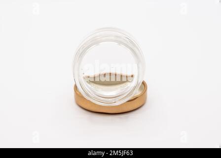Primo piano di una piccola marmellata vuota e pulita conserva il vaso di vetro con un coperchio metallico a vite color bronzo Foto Stock
