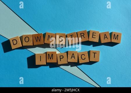 Impatto a valle, parola di buzzword commerciale in lettere di alfabeto di legno isolato su sfondo blu Foto Stock