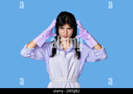 donna caucasica in guanti di gomma isolati su sfondo blu. Foto Stock