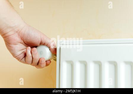 Ottimismo del clima e controllo del clima . Un uomo commuta la temperatura sulle batterie. Consente di risparmiare calore. Protegge l'ambiente. Foto Stock