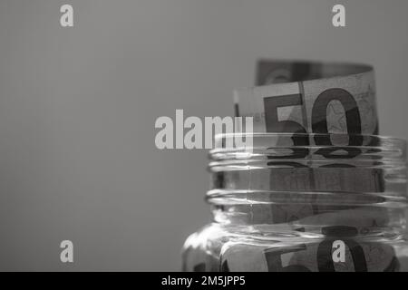 Composizione con banconote di risparmio (50 EURO) in un vaso di vetro. Concetto di investimento e di mantenimento del denaro, primo piano isolato. Foto Stock