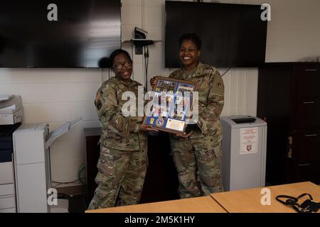 Staff Sgt. Kierra Magee (a sinistra), Material Manager, 1st Theater Sostainment Command, presenta un premio al Master Sgt. Alaine Gilpin (a destra), responsabile non incaricato della fornitura e dell'assistenza, 1st TSC, durante una cerimonia a Fort Knox, Kentucky, 21 marzo 2022. Gilpin ha ringraziato i suoi amici e la sua famiglia per il loro continuo sostegno durante la sua carriera. Foto Stock