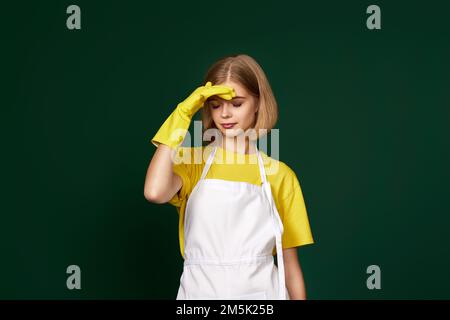 donna stanca con guanti gialli e grembiule più pulito Foto Stock