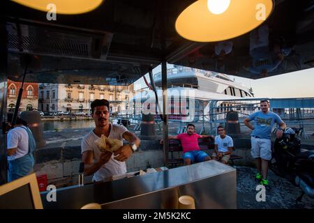 09-18-2015 Siracusa. Italia. Cuoco Dammi un panino o un hot dog di qualche tipo (non identificabile) vicino al Ponte Santa Lucia e alla Città Vecchia di Siracusa Foto Stock