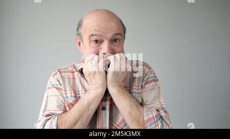 Uomo ispanico anziano che osserva stressato e nervoso con le mani sulle unghie mordenti della bocca. Foto Stock