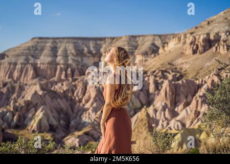 Giovane donna che esplora la valle con formazioni rocciose e grotte delle fate vicino a Goreme in Cappadocia Turchia Foto Stock