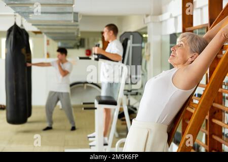 Donna matura che si stretching in palestra Foto Stock