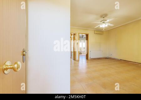 Sala di una casa con porta blindata e accesso ad un soggiorno vuoto con pavimenti in gres Foto Stock