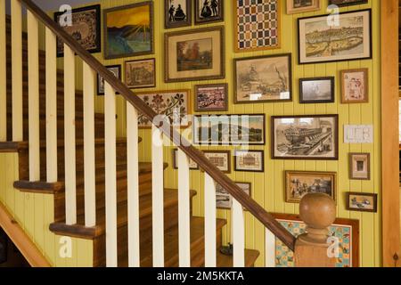 Parete con scala decorata con cornici a quadri nella sala da pranzo all'interno di una casa in legno in stile cottage di campagna. Foto Stock