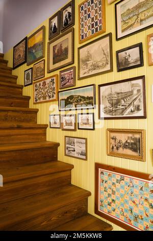 Parete con scala decorata con cornici a quadri nella sala da pranzo all'interno di una casa in legno in stile cottage di campagna. Foto Stock